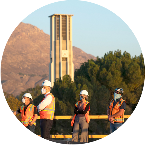 Chancellor Wilcox observing a construction site with 3 other workers wearing safety vests and helmets